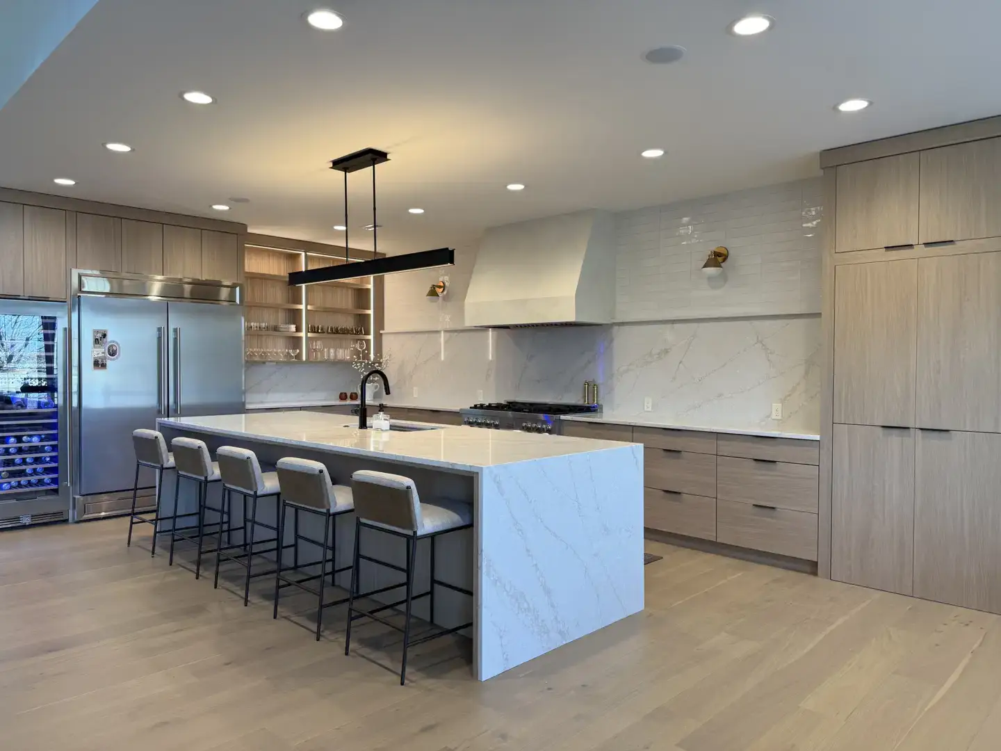 Modern kitchen island with waterfall countertop and bar stools.