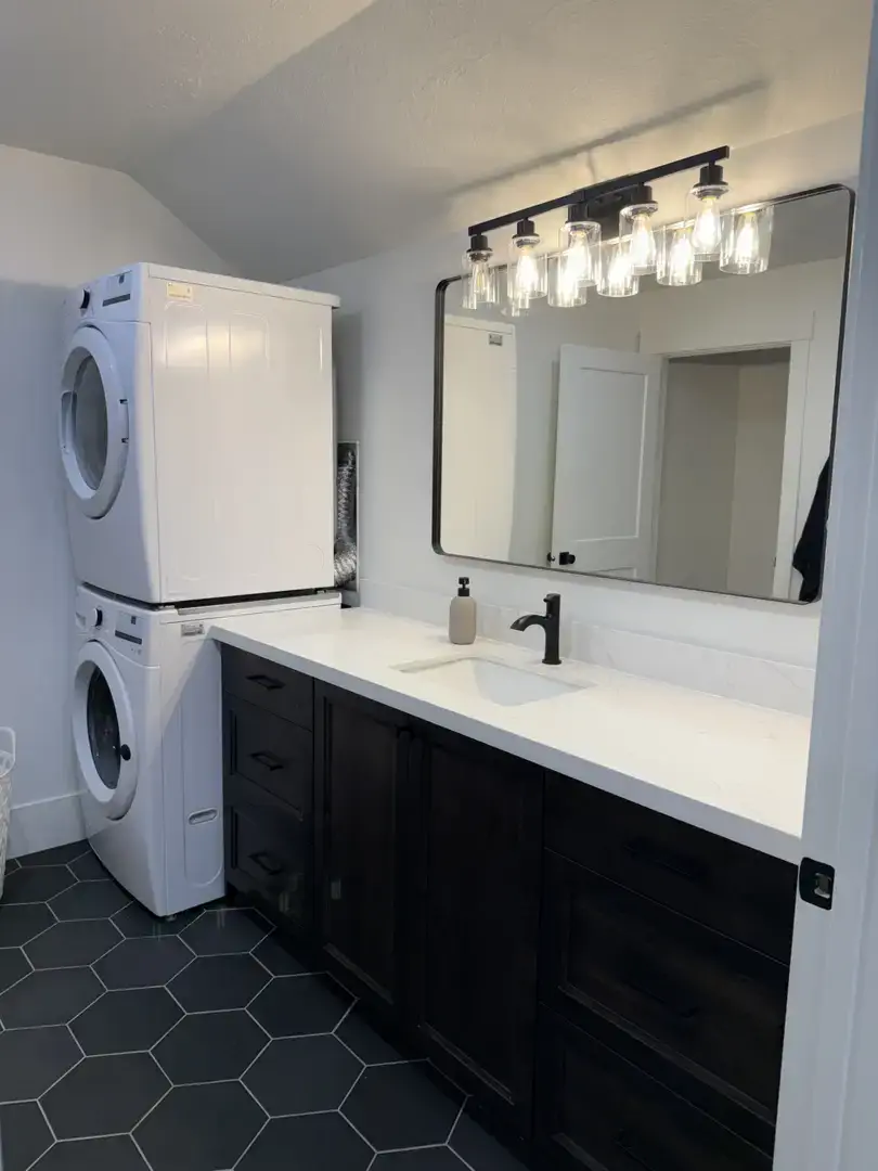 Modern laundry room vanity with dark cabinets and white countertop in Slaterville, Utah.