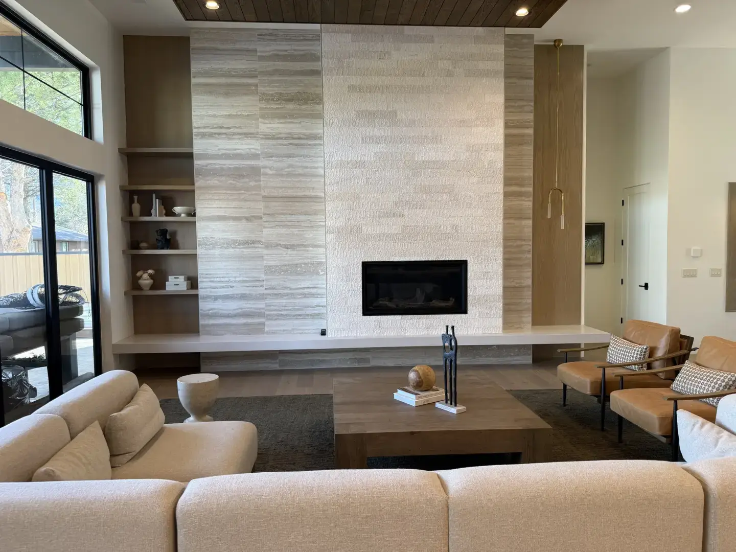 Modern living room with a large stone fireplace and built-in shelves.