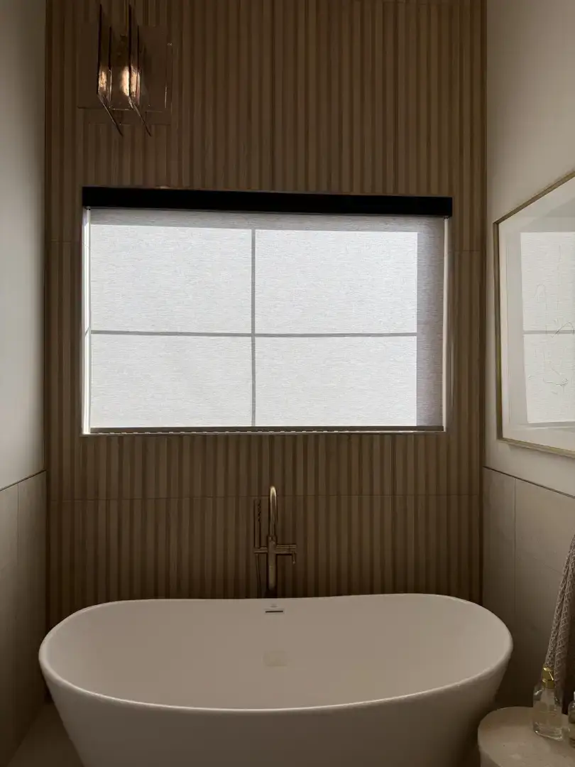 Modern freestanding bathtub with brass faucet and fluted wood accent wall.